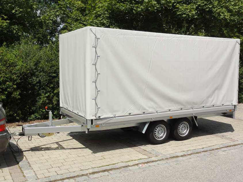 Kastenhochladeranhänger auf Tandemfahrgestell mit Plane und Spriegel.