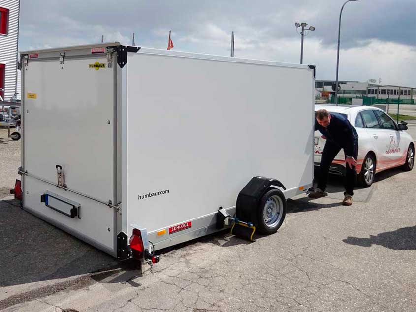 Senkliftanhänger als Koffer mit Flügeltüren auf Tandemfahrgestell und Rampe aus Riffelblech.